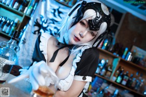 A woman in a maid outfit sitting at a bar.