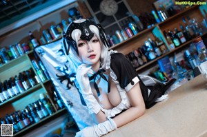 A woman in a maid outfit standing at a bar.