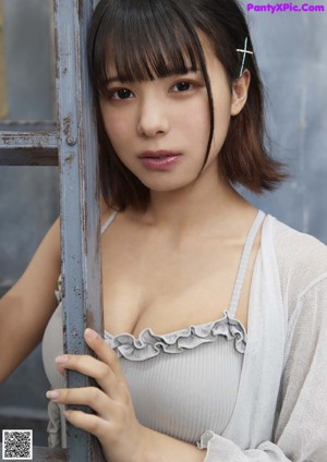 A woman in a gray bodysuit leaning against a ladder.