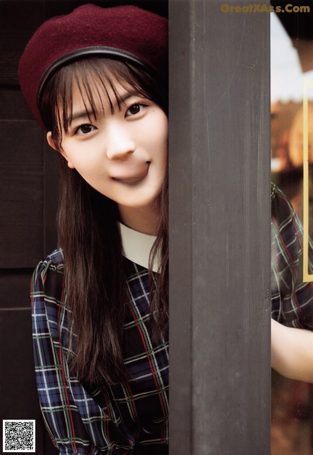 A young woman wearing a red beret leaning against a wall.