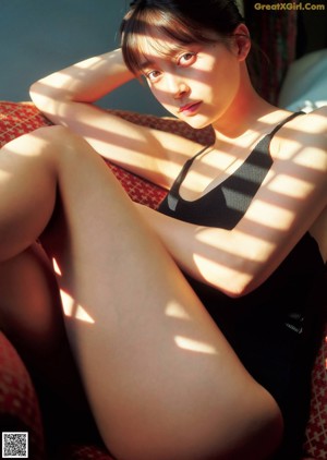 A woman in a pink bikini sitting on a wooden floor.