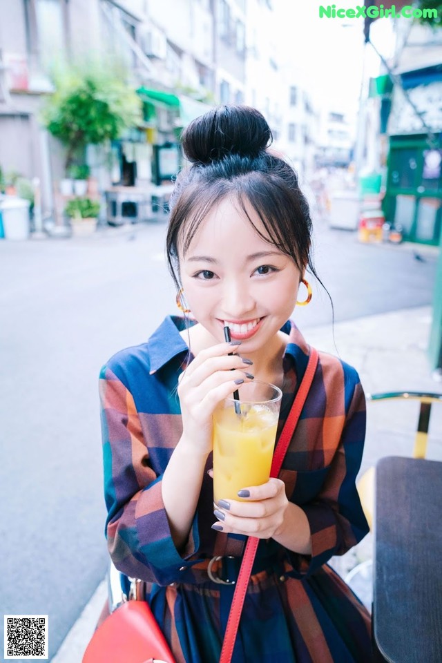 A woman holding a glass of orange juice in her hand.