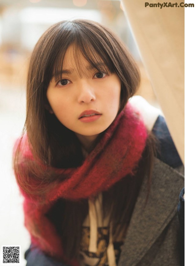 A woman wearing a red scarf is looking at the camera.