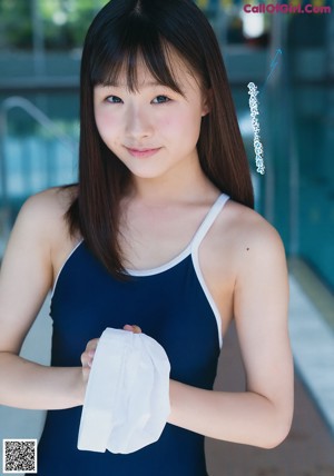 A woman in a blue bathing suit standing next to a pool.