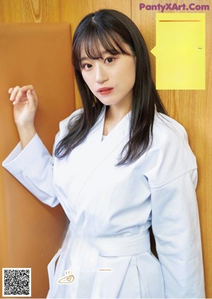 A woman in a white kimono is practicing karate. 