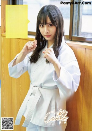 A woman in a white kimono is practicing karate. 