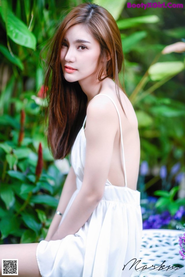 A woman in a white dress sitting on a bench.