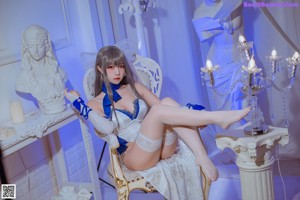 A woman in a white and blue lingerie sitting on a chair.