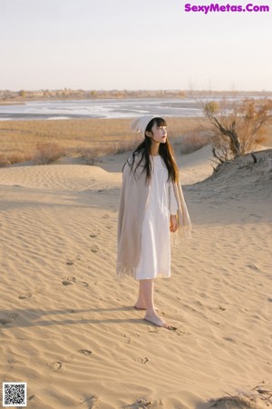 A woman sitting on the ground next to a tree.