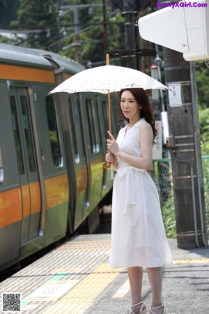 A woman in a white dress laying in the grass.