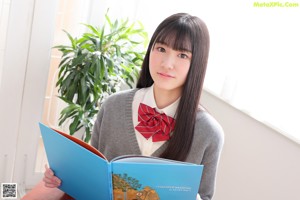 A young woman in a school uniform sitting on a chair.