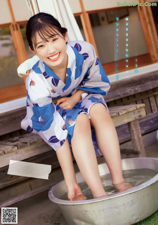 A woman in a blue and white kimono sitting in a metal tub.