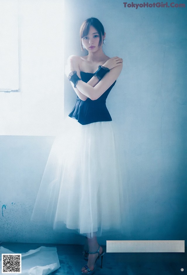 A woman in a black top and white skirt posing for a picture.