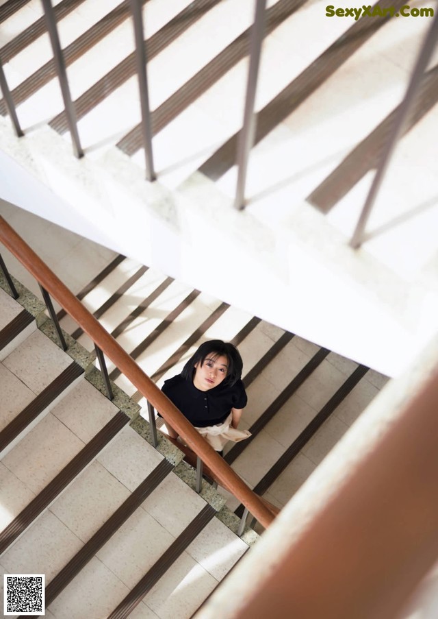 A woman is sitting on the stairs of a building.