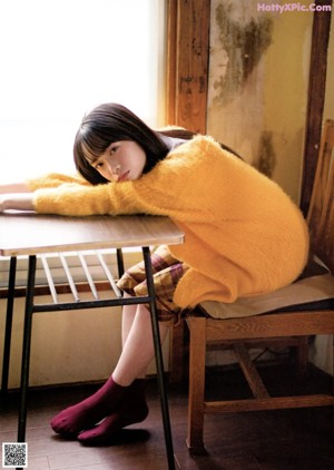 A young woman in a blue sweater is looking at the camera.