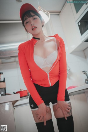 A woman in a red shirt and black shorts holding a box.
