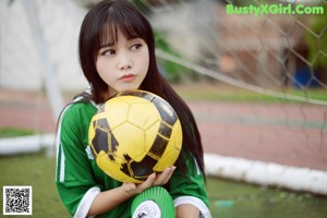 A young woman holding a soccer ball on a field.