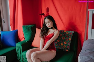 A woman in a red bathing suit sitting on the floor next to a Christmas tree.