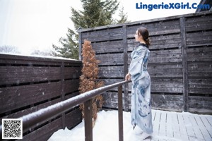 A woman in a blue kimono standing in the snow.