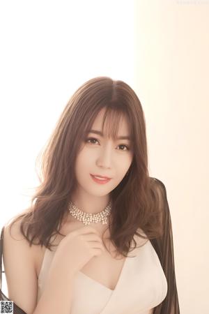 A woman in a white tank top posing for a picture.