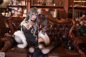 A woman in lingerie sitting on a chair in front of a bookcase.