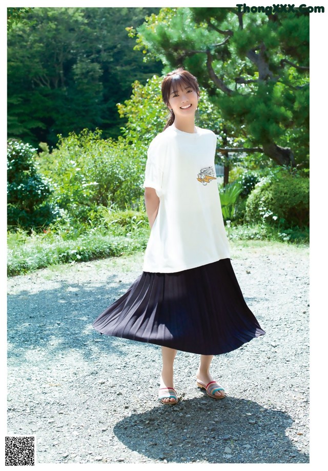 A woman wearing a white shirt and a black pleated skirt.