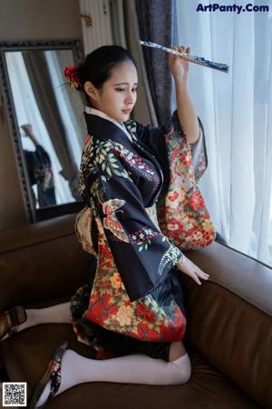 A woman in a kimono sitting on a couch.