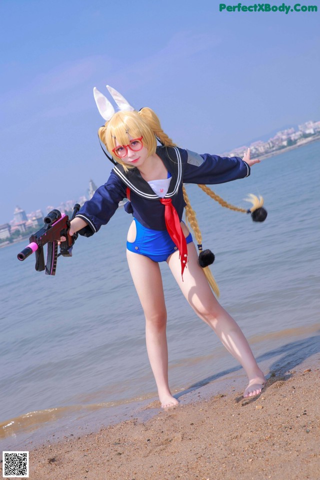 A woman in a bunny costume holding a gun on the beach.