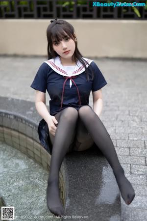 A woman in a school uniform sitting on a ledge.