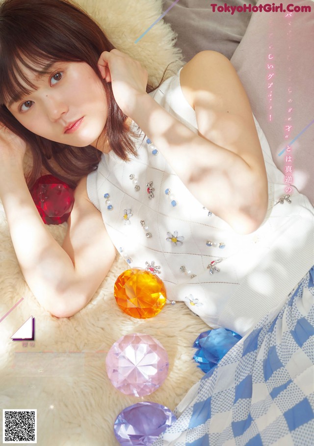 A woman laying on top of a bed next to a pile of colorful gems.