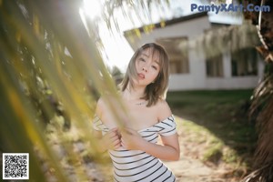 A woman in a colorful bathing suit leaning against a fence.