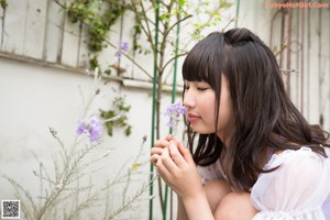 A woman in a white dress crouching down in the grass.