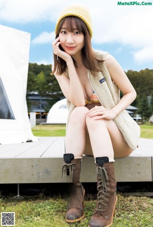 A woman sitting on top of a bench next to a car.