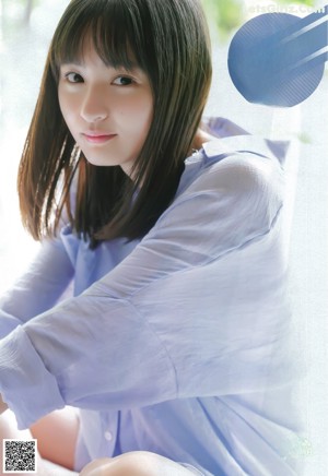 A young woman in a school uniform crouching on the ground.