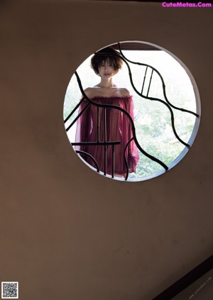 A woman in a red dress sitting on a window sill.