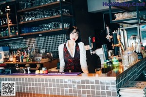 A woman sitting at a bar smoking a cigarette.