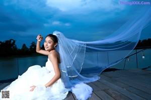 A woman in a wedding dress standing on a dock.